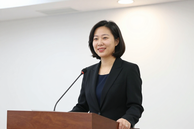 专业亚洲女性讲师微笑面对镜头，商务演讲场景